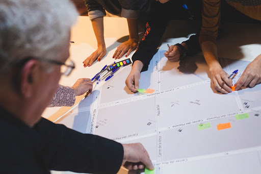 People adding coloured sticky labels to large pieces of paper as part of a workshop activity