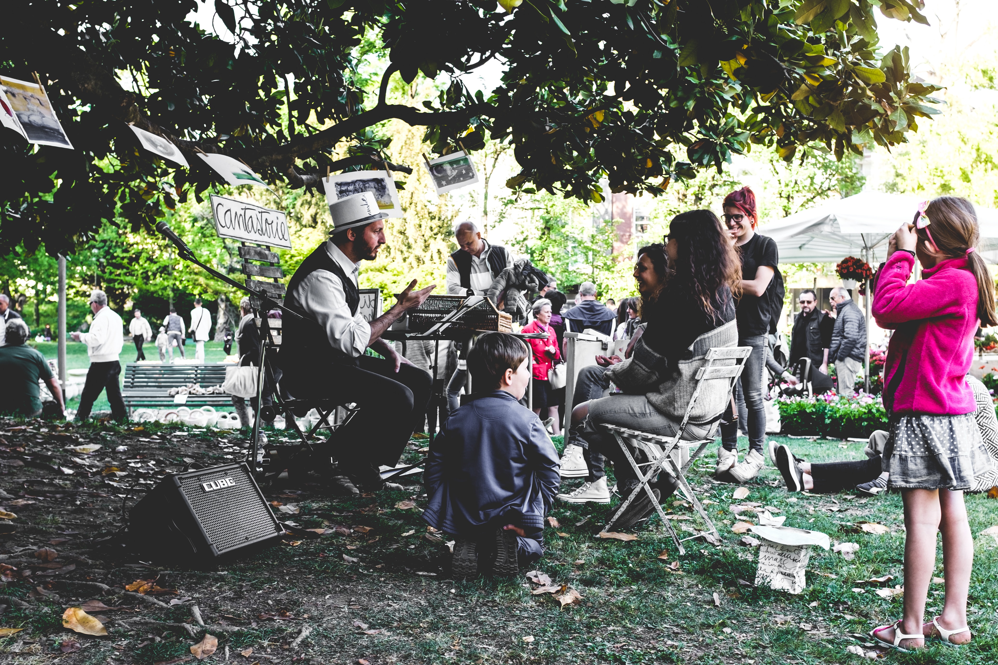 Man tells a story in a park. Many people listen.